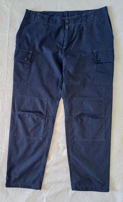 un pantalon cargo bleu marine posé sur un lit recouvert d'un drap blanc