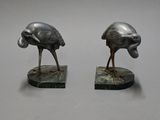 pair of bronze sculptures of two birds on a marble base