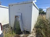 une cabane de toilettes blanche au milieu d'un champ