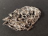 a close up of a silver chain with a skull on it