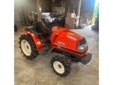 un tracteur rouge garé dans un garage avec un gros pneu