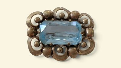 an image of a brooch with a blue topaz stone in it