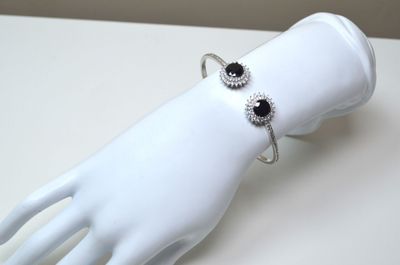 une main de mannequin blanche portant un bracelet noir et blanc