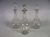 three clear glass bottles sitting on top of a table next to each other