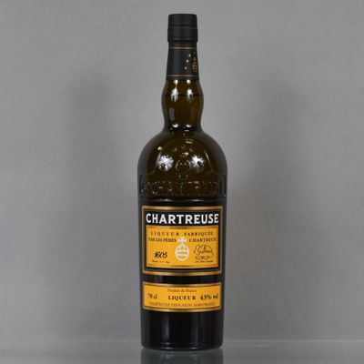 the bottle of chartreuse is sitting on a glass table