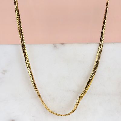 un collier à chaîne en or posé sur une surface en marbre
