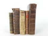 several old books are stacked on top of each other on a white surface