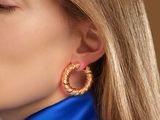 the woman is wearing a blue shirt and gold hoop earrings