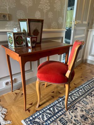 une chaise rouge placée devant un bureau sur lequel se trouve un miroir