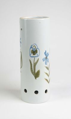 un vase blanc orné de fleurs bleues, posé sur un fond blanc
