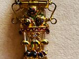 a gold necklace with a clock on it on a white surface