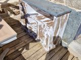 une table en bois posée sur une terrasse en bois, avec un mur en pierre en arrière-plan