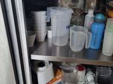 a stainless steel shelf with cups and containers on it