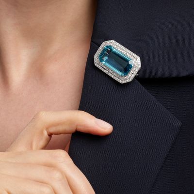 the lapel of a woman wearing a ring with a blue topaz stone