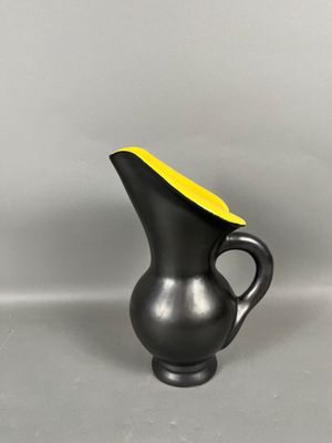 a black vase with a yellow top on a gray surface