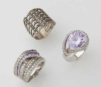 three rings and a ring with diamonds on a white surface