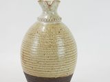 a brown and black vase sitting on a white surface