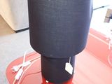 une table rouge sur laquelle est posée une lampe noire