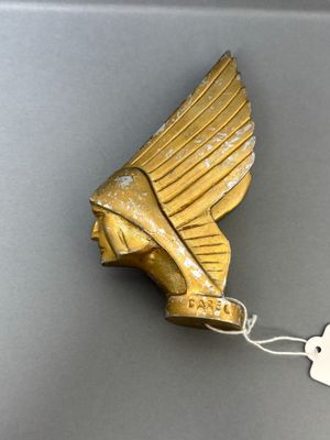 an image of a gold statue of a winged head with a tag attached to it