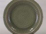 une assiette verte ornée d'un motif, posée sur un support en bois