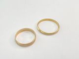 two gold wedding rings on a white surface