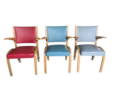 quatre chaises colorées sont alignées en rang sur un fond blanc