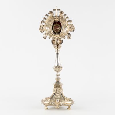 a silver and red clock on a stand on a white background