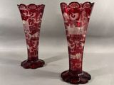 pair of red glass vases sitting on top of a white table