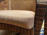 a wicker chair with a cushion on it in a room
