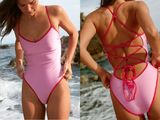 a woman in a pink one piece swimsuit on the beach