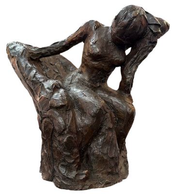 statue d'une femme assise sur une chaise, les jambes croisées