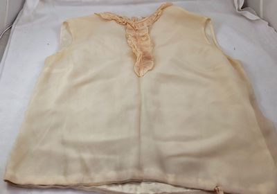 cream colored top with lace trim on top of a white bed