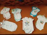 many baby clothes laid out on a table in a crib