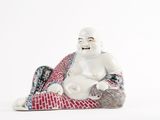 a figurine of a laughing buddha sitting on a blanket