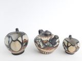 three pieces of pottery sitting on a white surface