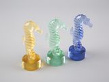 trois figurines d'hippocampes en plastique posées sur une surface blanche