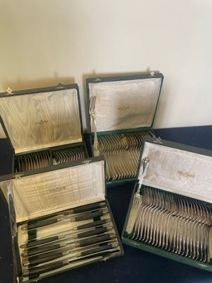 several silverware in a case sitting on a table next to a wall