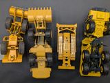 four toy construction vehicles that are lined up on a table