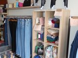 a woman standing in front of a closet filled with lots of clothes