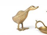 a gold duck statue next to a brass candle holder