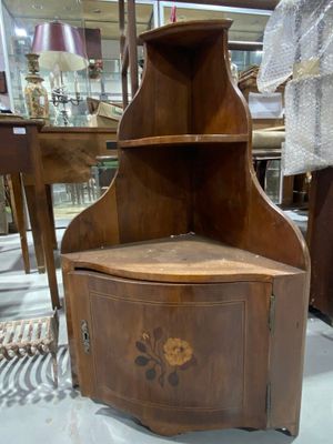 a wooden corner cabinet with a drawer on top of it