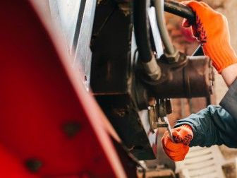 Une personne portant des gants orange est en train de travailler sur un véhicule.