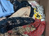 une boîte en carton remplie de vêtements, ainsi que des vêtements éparpillés par terre