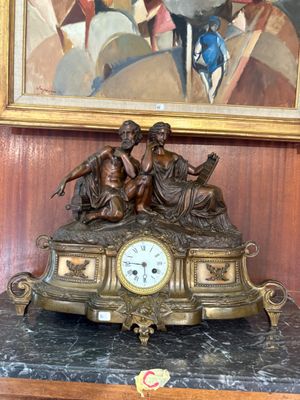 a clock on a table in front of a painting