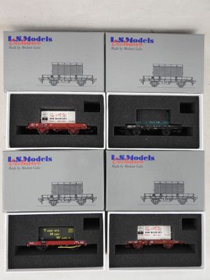 six boîtes contenant des wagons de train miniature, exposées sur une surface blanche