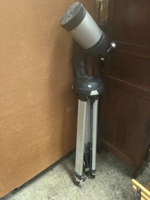 un télescope noir et argenté posé sur un trépied, à côté d'une porte marron