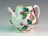 a white tea pot with green and pink flowers on it