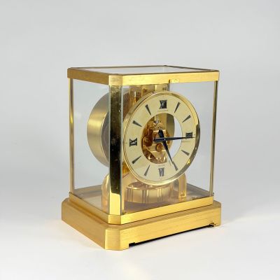 a gold clock that is sitting on a white surface