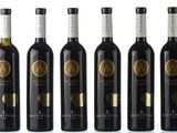 six bottles of wine are lined up on a white surface