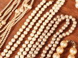 many pearls and other jewelry on a wooden table